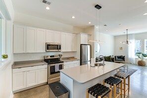 A modern kitchen with white cabinets, stainless steel appliances, and a central island with stools. - 7 Mi to Dtwn Nashville: Modern Madison Townhome (Madison)