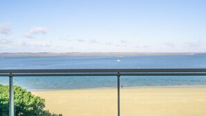 A beach view from a balcony with a clear sky and calm sea.