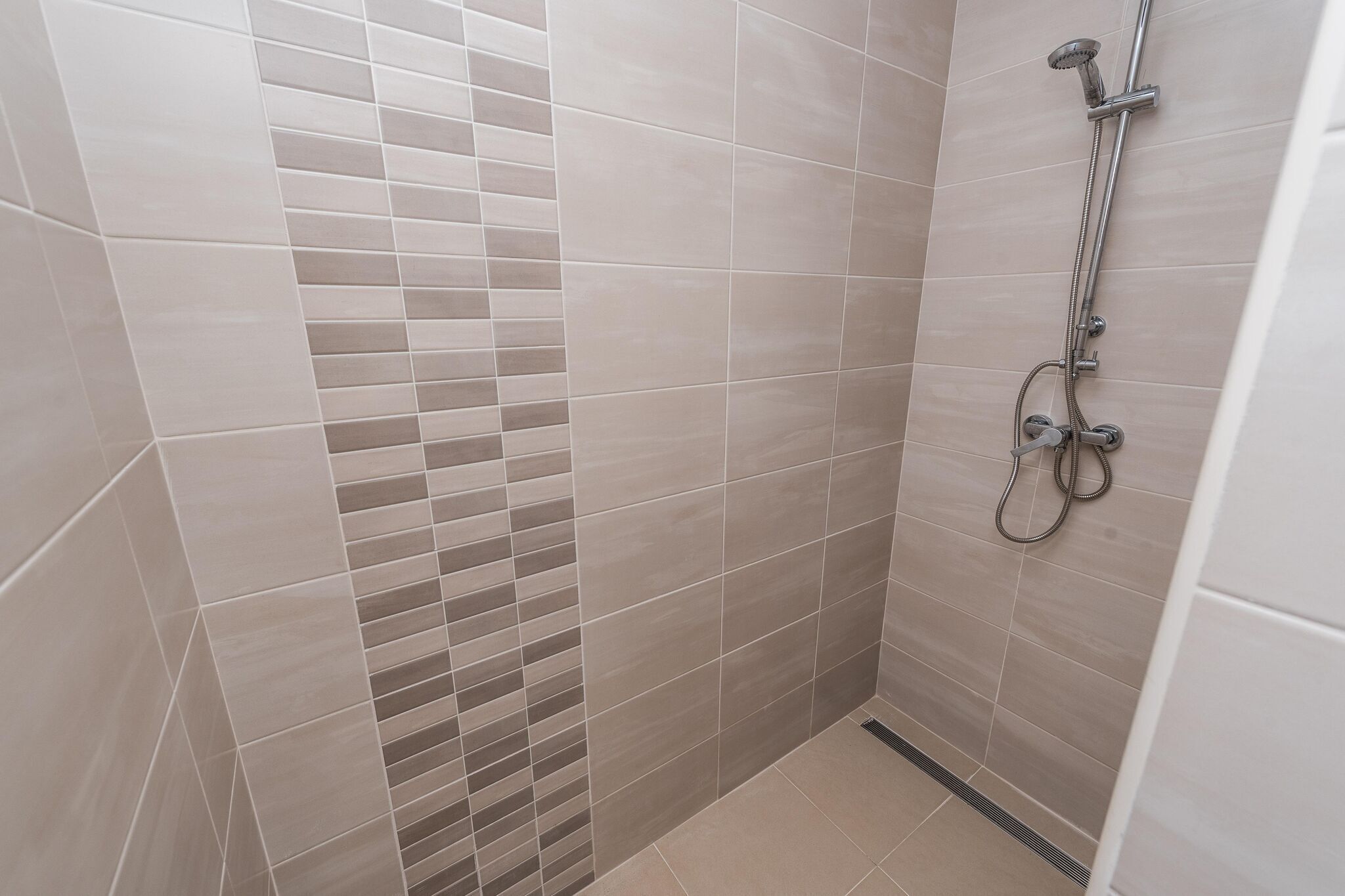 A shower area with tiled walls and a showerhead.