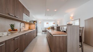 A modern kitchen with wooden cabinets, a central island, and a dining area with a table and chairs. - Nicely decorated villa with swimming pool (Sukosan)