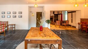 A spacious dining area with a large wooden table, red vase centerpiece, and modern pendant lighting. - Charming Chalet in Falaën by River & Château (Falaën)