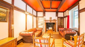 A traditional room with a fireplace, leather sofas, and striped chairs. - Charming Chalet in Falaën by River & Château (Falaën)
