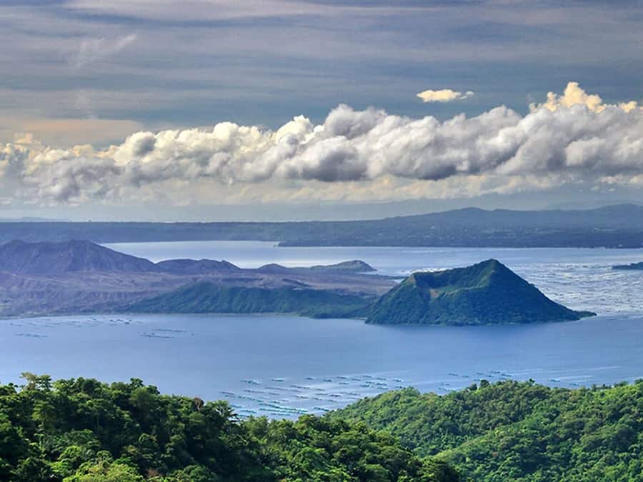 Un paisaje costero con montañas, una extensa masa de agua y una isla verde destacada.