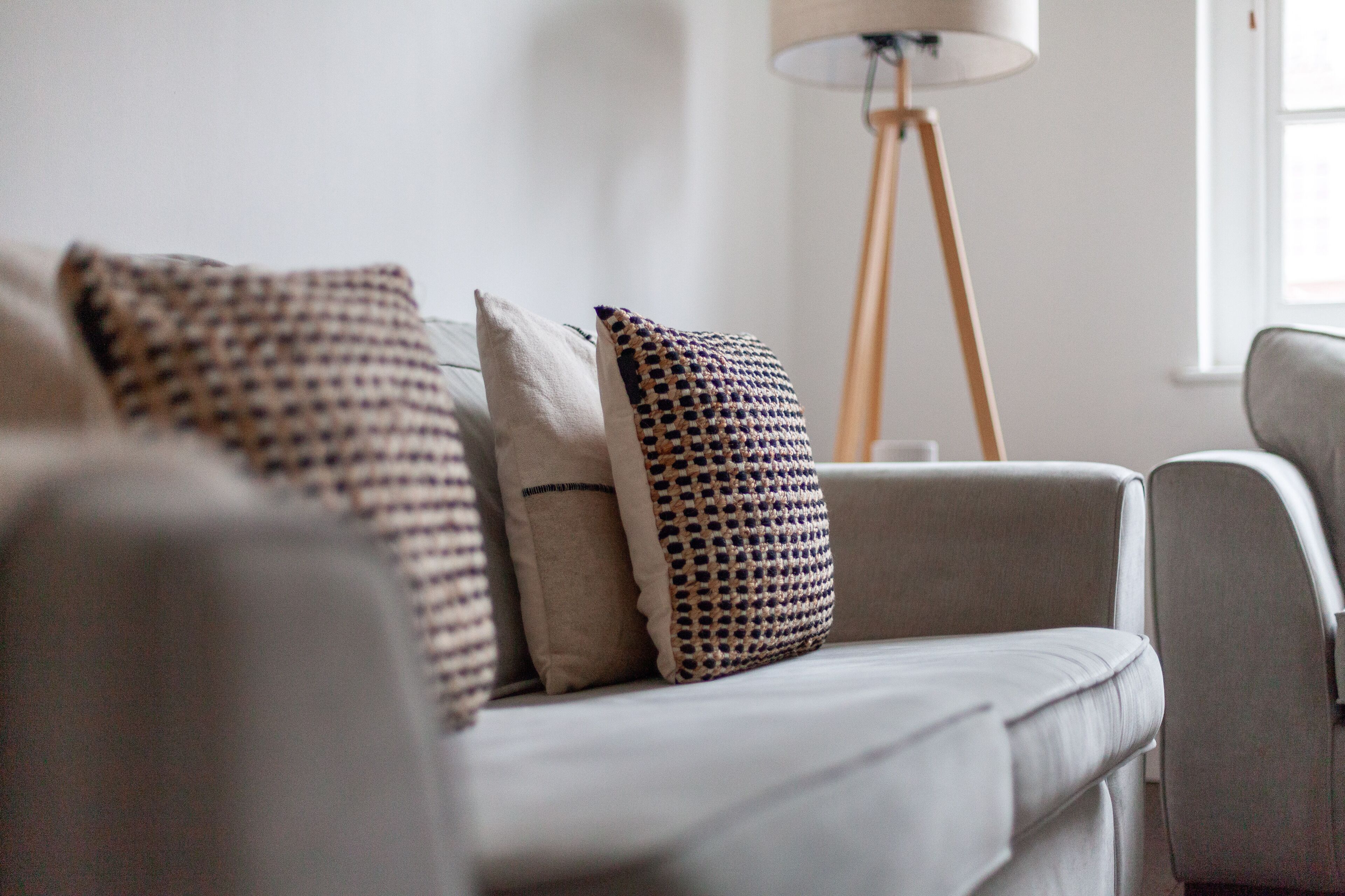 Ein modernes Wohnzimmer mit einer Couch, gemusterten Kissen und einer Stehlampe.