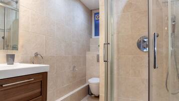 A modern bathroom with a glass-enclosed shower, a wooden vanity, and a toilet.