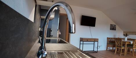 A modern kitchen with a stainless steel sink, a built-in stove, and a wooden dining table with chairs.
