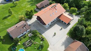An aerial view of a property with a large building, a swimming pool, and surrounding greenery. - Nr. 1 Neubau Ferienwohnung mit 2 Sep. Schlafzimmern, Ost-balkon, 75qm (Prien am Chiemsee)