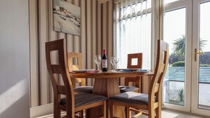 Un comedor con una mesa y sillas de madera, un cuadro en la pared y vistas por una ventana.