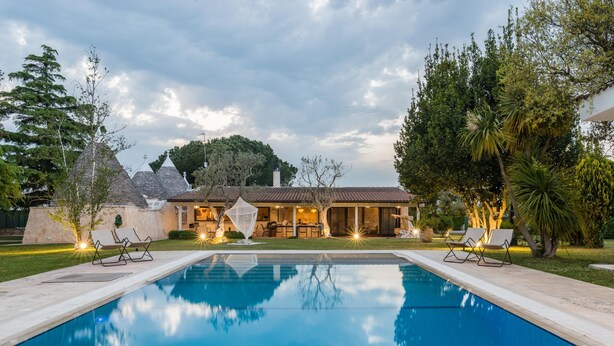 A swimming pool with lounge chairs, a house with a tiled roof, and surrounding greenery. - 3676 Villa Enò by Perle di Puglia (Noci)