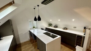 A modern kitchen with a central island, dark cabinetry, and pendant lighting.