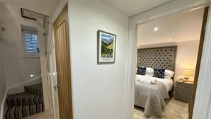 A hotel room with a bed, a nightstand, a lamp, and a framed picture on the wall.