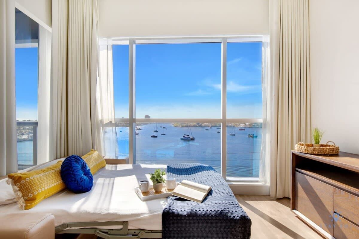 A room with a large window offering a view of boats on water.