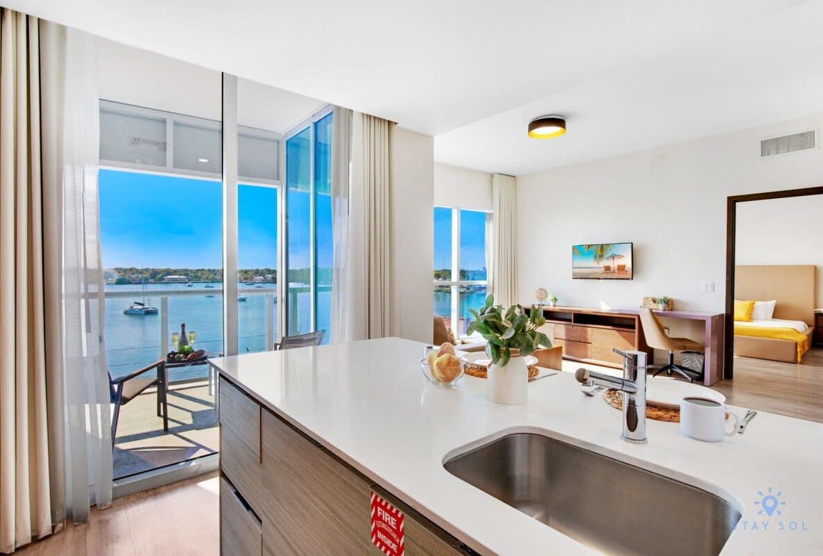 A modern hotel room with a large window offering a view of the sea and boats.