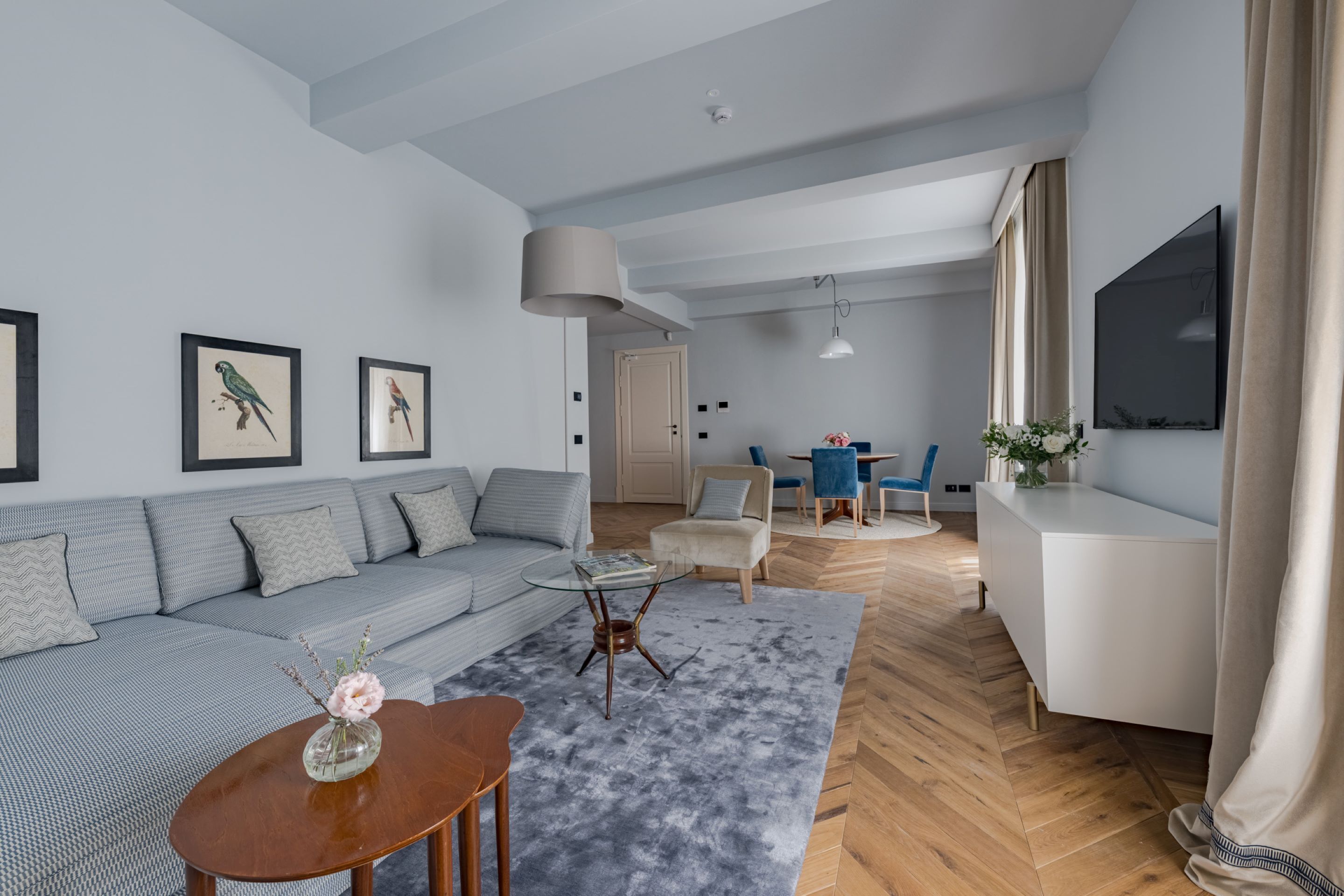 Un salon moderne avec un canapé gris, une table basse et un téléviseur fixé au mur.