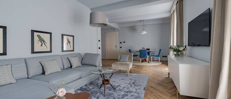 Un salon moderne avec un canapé gris, une table basse et un téléviseur fixé au mur.