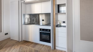 A compact kitchen with integrated appliances, including a stainless steel refrigerator, oven, and sink, in a modern white cabinetry design. - Palazzo Signoria Luxury Apartments (Florence)