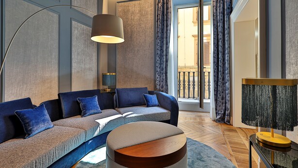 A modern living room with a sectional sofa, a round coffee table, and a floor lamp. - Palazzo Signoria Luxury Apartments (Florence)