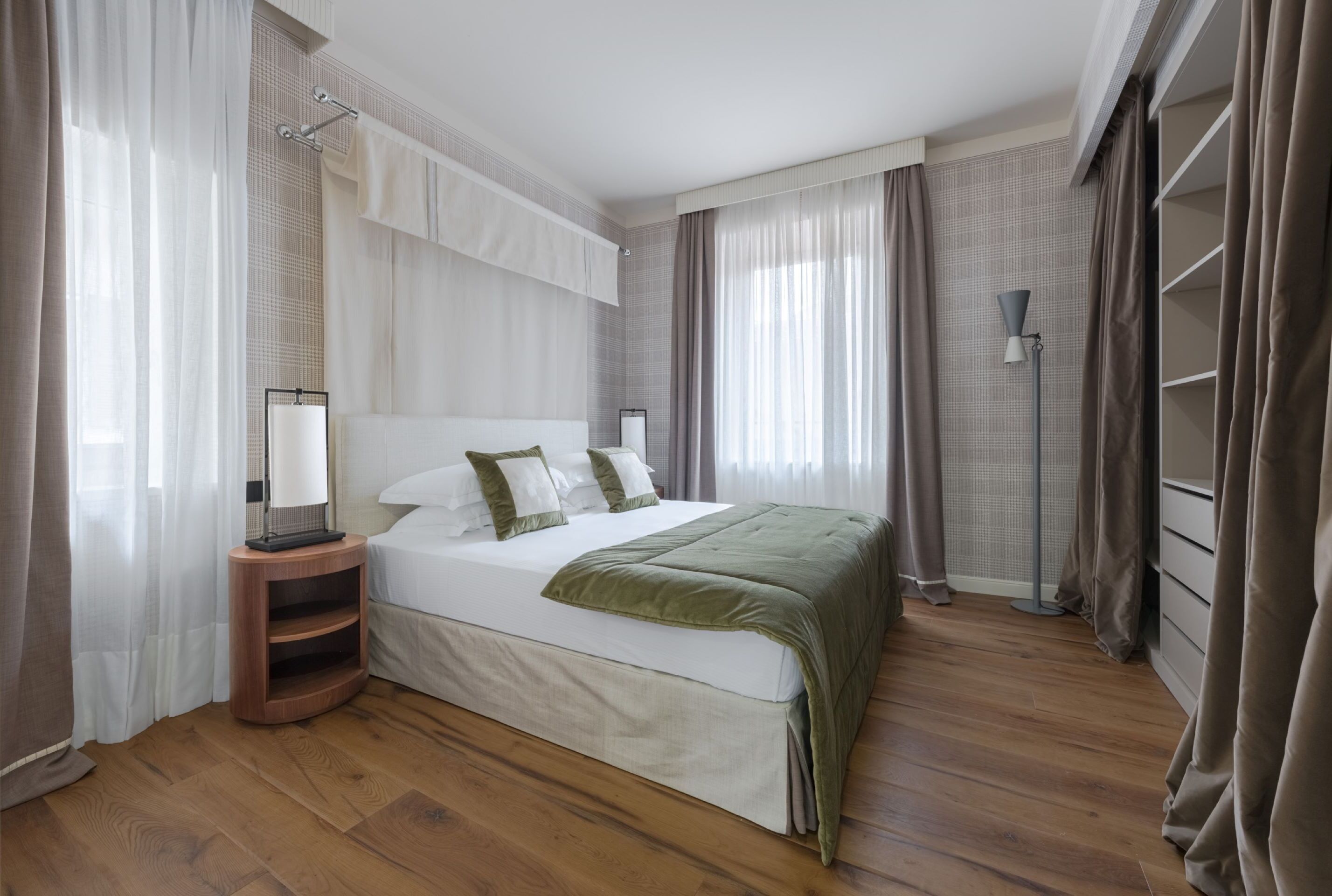 A modern bedroom with a large bed, wooden flooring, and a built-in wardrobe.