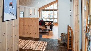 Een gezellige kamer met een houten plafond, een groot raam, een bank en een tafel met een plaid.