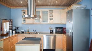 Een moderne keuken met houten kastjes, een roestvrijstalen afzuigkap, een vaatwasser en een koelkast.