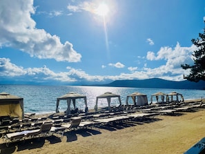 Ein Strand mit Liegestühlen und Sonnenschirmen, einem klaren Himmel und ruhiger See.
