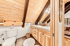 Casa de banho com painéis de madeira, vaso sanitário, lavatório e armários.