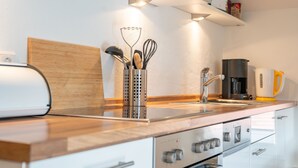 A modern kitchen with stainless steel appliances, wooden countertops, and a built-in oven. - Ferienwohnung Da Dachstui 60 Qm,1 Schlafzimmer, Wohnschlafraum, bis 6 Personen (Samerberg)