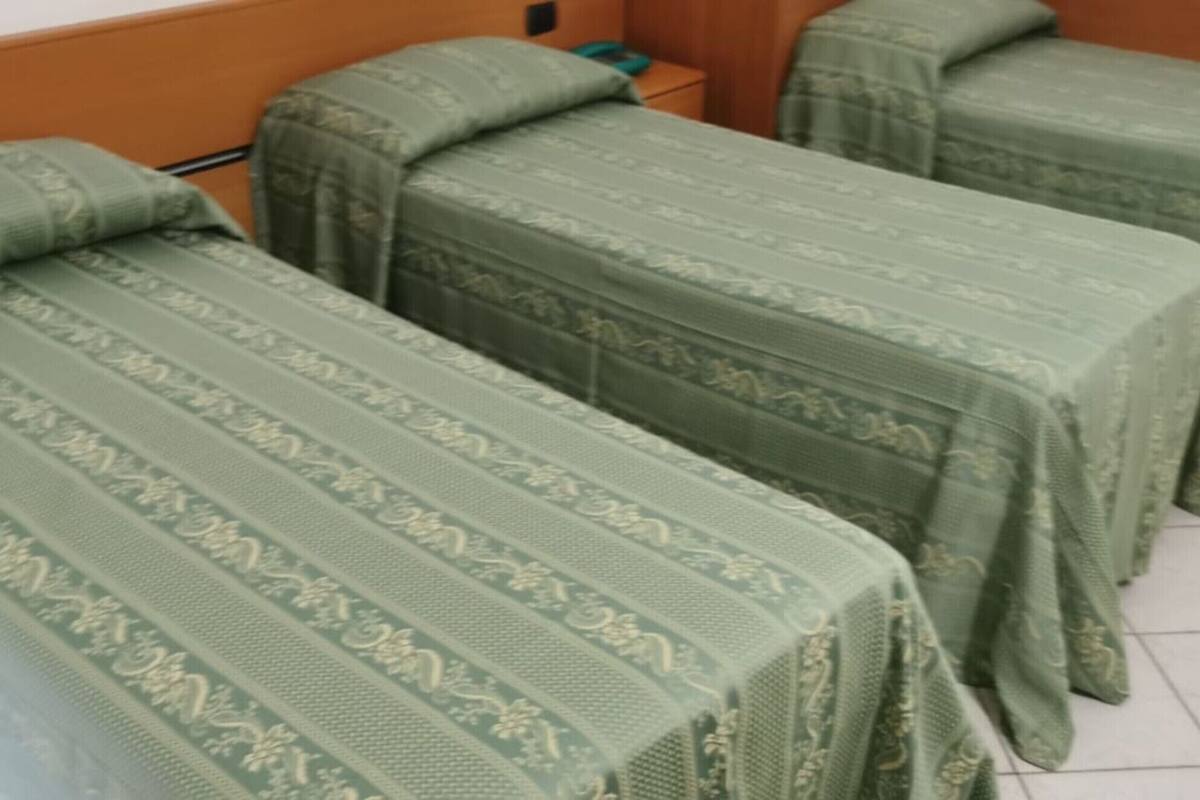 Habitación con tres camas cubiertas con colchas estampadas en verde.