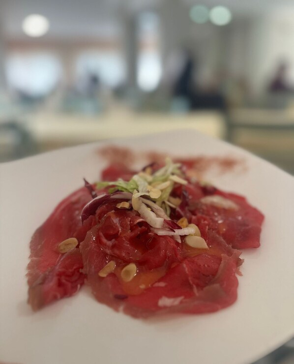 A plate of raw meat with garnishes on a white plate. - Hotel San Francesco (San Giovanni Rotondo)