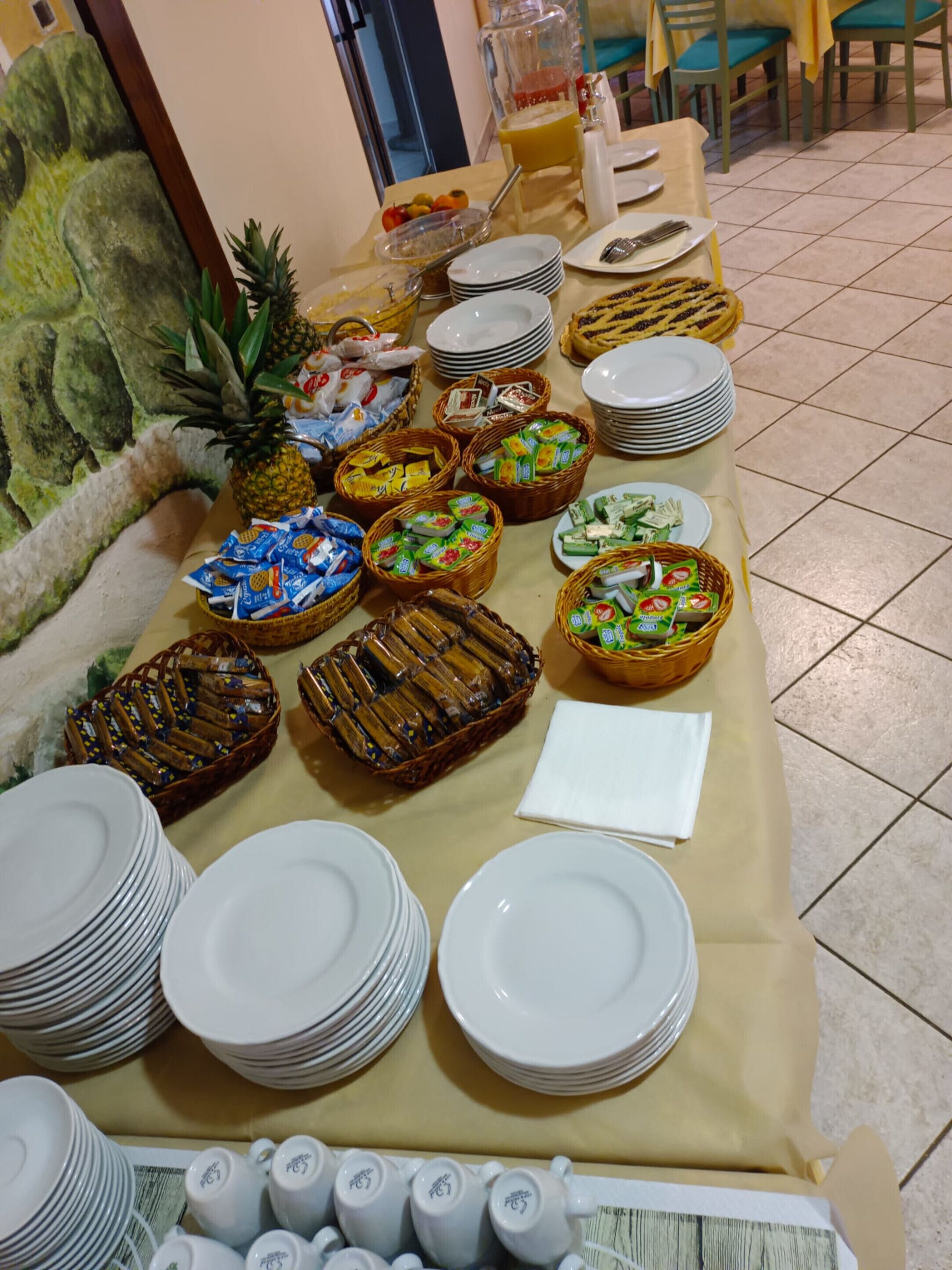 A buffet table with various food items and stacked plates.