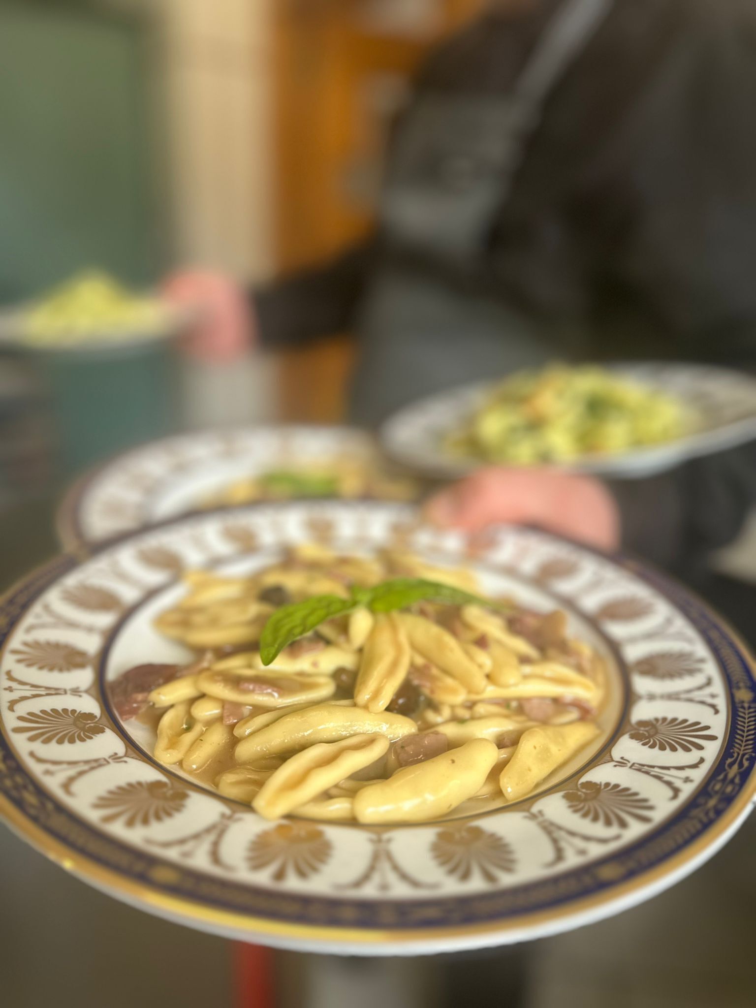 Ein Nahaufnahme eines Tellers mit Pasta und einem Minzblatt als Garnitur.