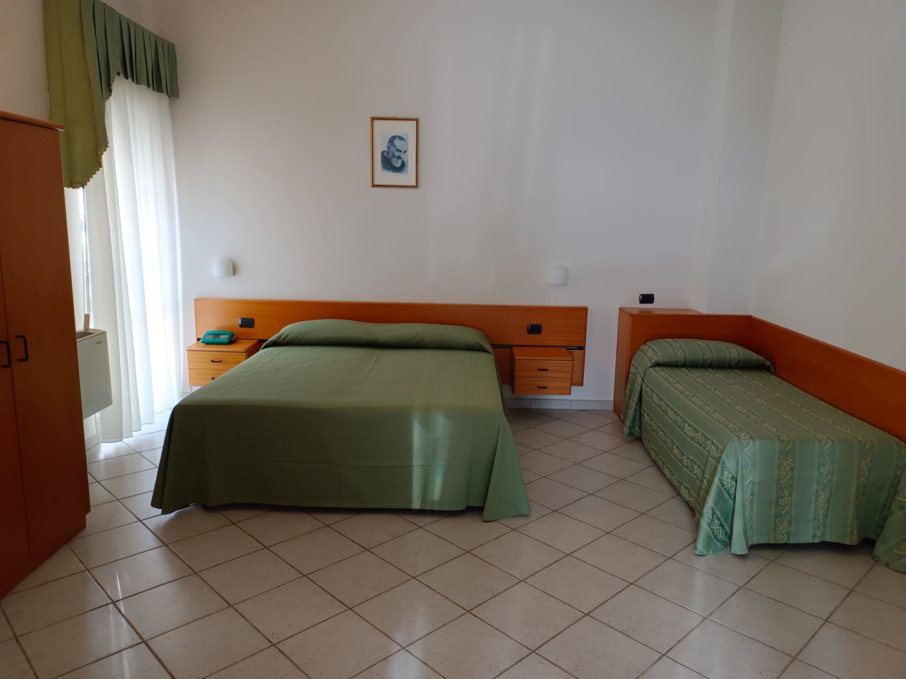 A room with two beds, a nightstand, a small table, and a framed picture on the wall.
