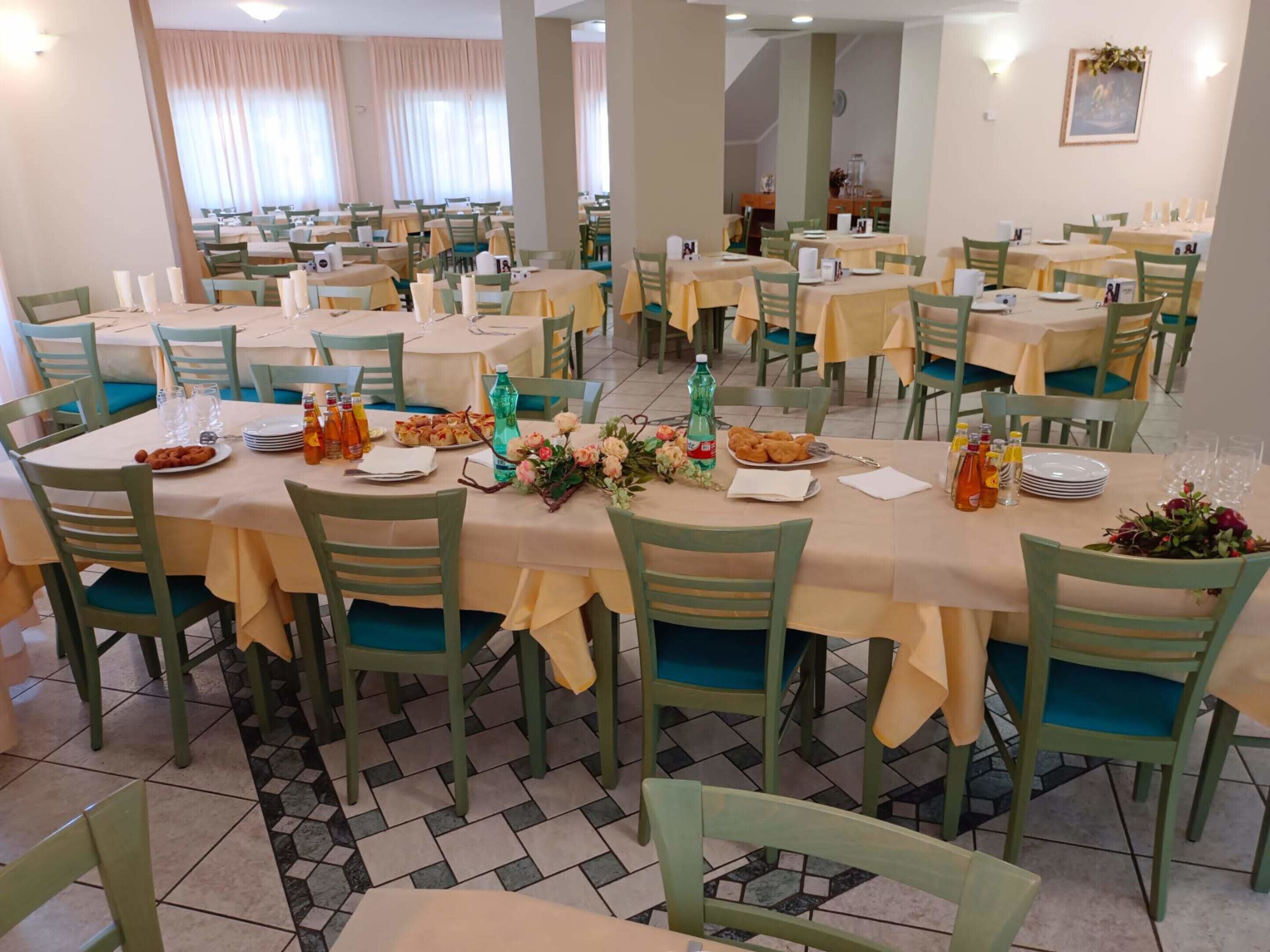 A dining area with multiple tables set for meals, each with chairs and table settings.