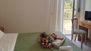 Een hotelkamer met een bed, een bureau, een stoel en een balkon met uitzicht.