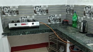 Een keuken met een gasfornuis, een waterkoker, een gasfles en een groene fles.