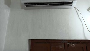 Een witte airconditioningunit aan een muur bevestigd, met een bruine deur eronder.