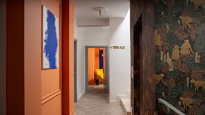A hallway with a herringbone floor, a blue abstract painting on the left, a sign reading "TERRACE" on the right, and a patterned wallpaper on the far wall. - Siesta Boutique Smart Suites (Cluj-Napoca)