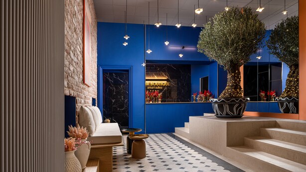 A modern hotel lobby with a blue accent wall, a marble fireplace, and a staircase leading to the upper floors. - Siesta Boutique Smart Suites (Cluj-Napoca)
