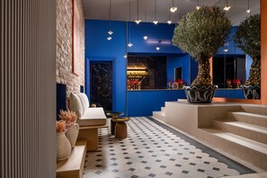 A modern hotel lobby with a blue accent wall, a marble fireplace, and a staircase leading to the upper floors. - Siesta Boutique Smart Suites (Cluj-Napoca)