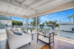 A spacious balcony with a white sofa, a wooden chair, and a glass table. - Casa Valentina - Marbellamar (Marbella)