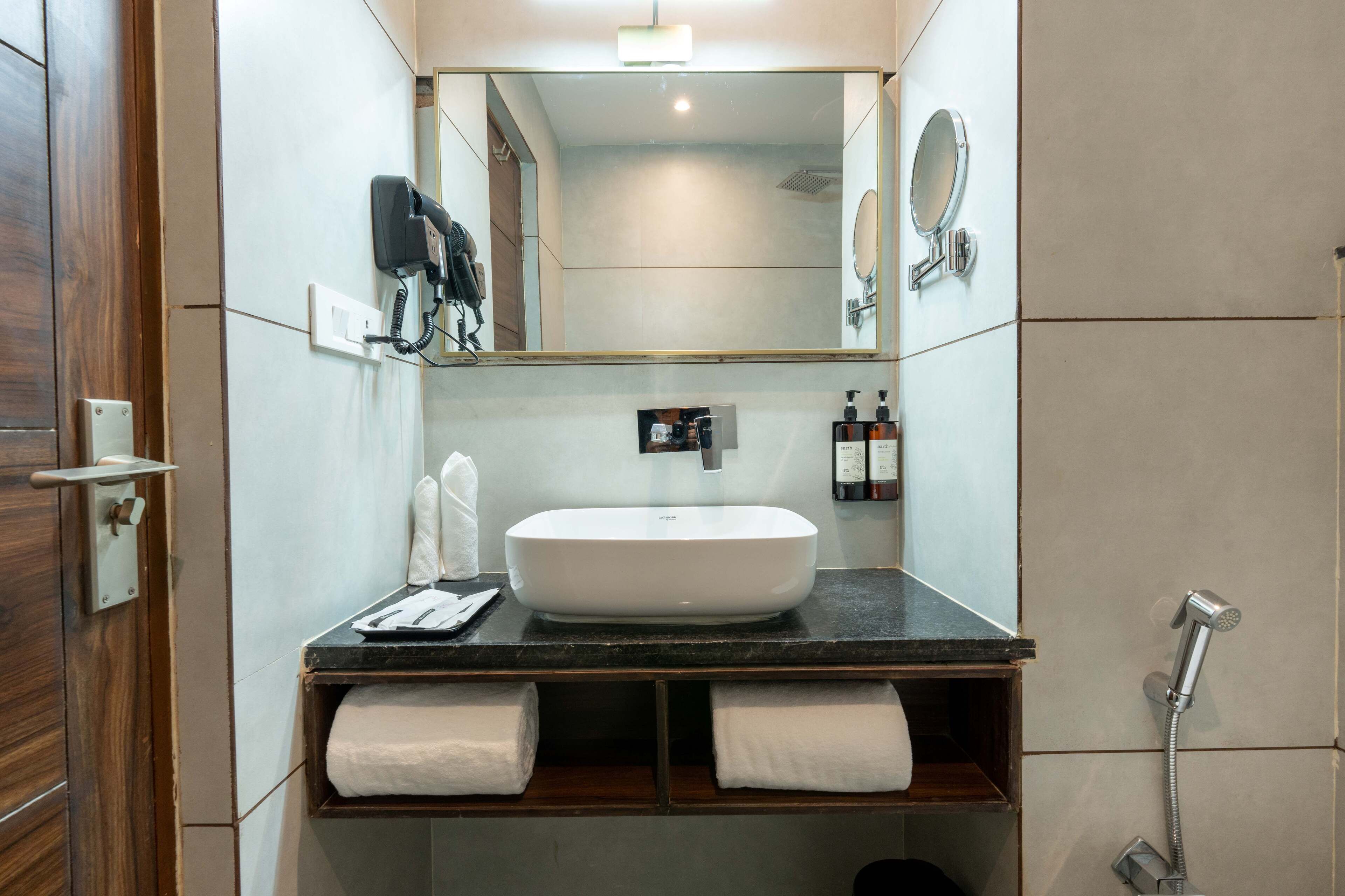 A modern bathroom with a large mirror, a white sink, and a shower.