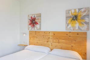 A bedroom with a wooden headboard, two white pillows, and two wall-mounted paintings of flowers. - Villa Lucas - Magnificent Sea Views (San Jaime Mediterráneo)