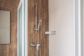 Eine Dusche mit Handbrause und am Wand befestigtem Wasserhahn.