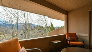 A balcony with two orange chairs, a small table, and a view of mountains. - Moab Indian Hills - Secluded Breathtaking Views (Moab)