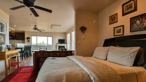 A bedroom with a large bed, a ceiling fan, and a view of the kitchen. - Moab Indian Hills - Secluded Breathtaking Views (Moab)
