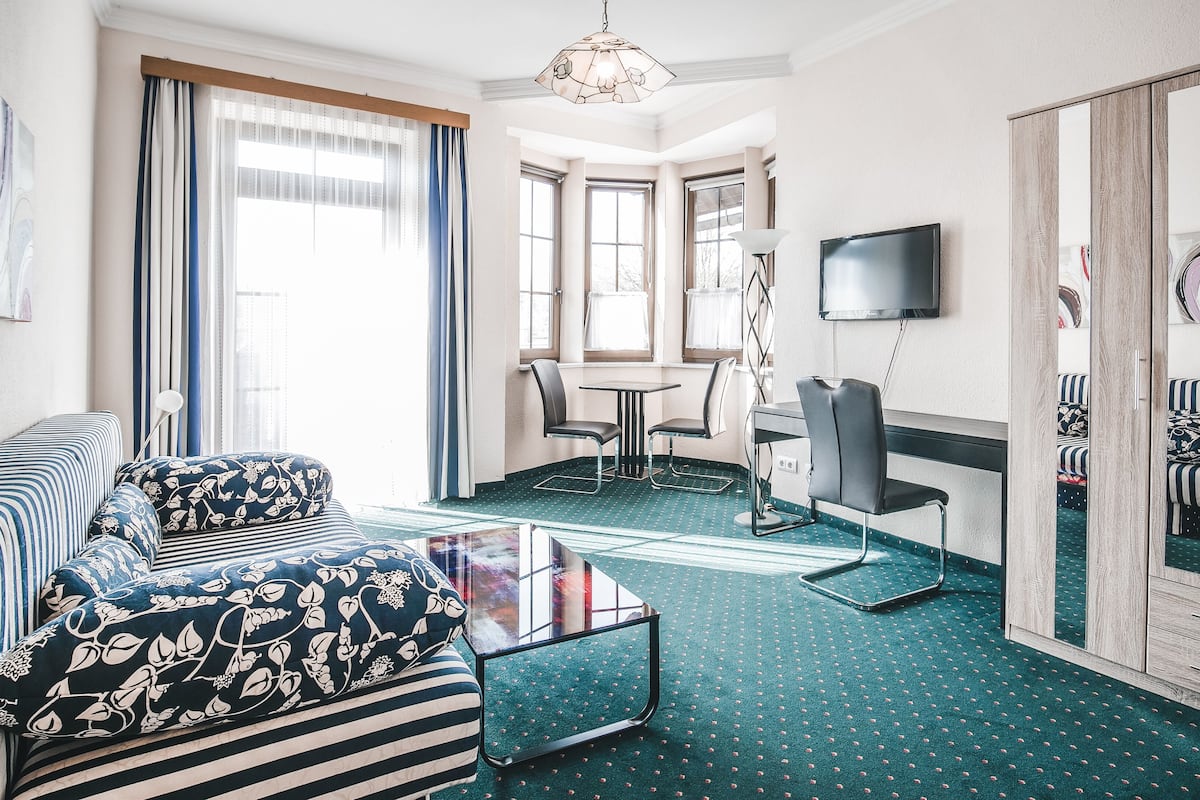 Habitación de hotel con sofá, una mesita, televisión y espejo.
