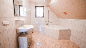 A modern bathroom with a sink, mirror, and bathtub. - Hotel Kärntnerhof Velden by S4Y (Velden am Wörther See)