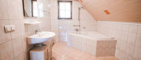 A modern bathroom with a sink, mirror, and bathtub.