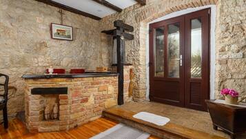 Un interior rústico de piedra con chimenea, suelo de madera y puerta de madera.