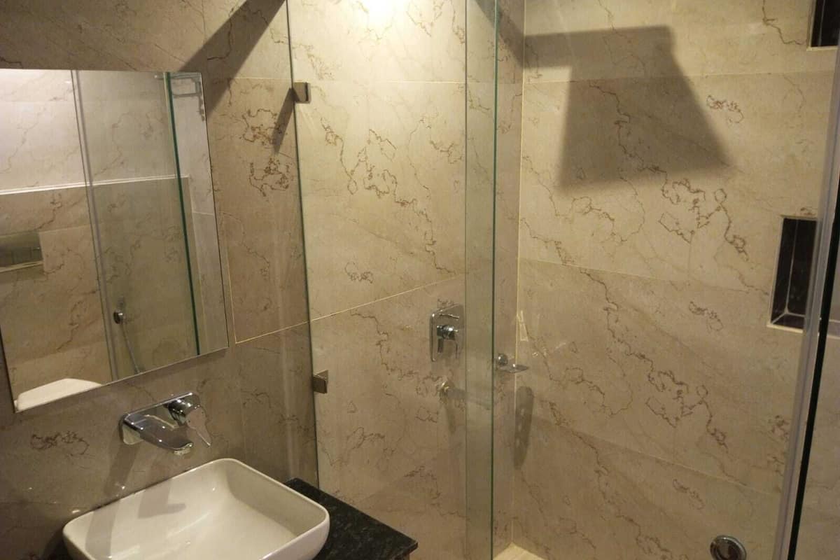 A bathroom with a glass-enclosed shower, a white sink, and a mirror.